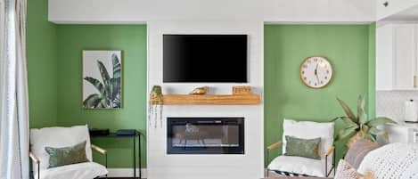 A living room with a fireplace, a flat-screen TV, and green walls.