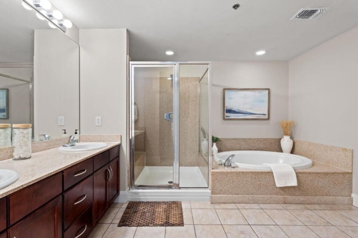 A modern bathroom with a glass-enclosed shower, a large bathtub, and a vanity with a mirror.