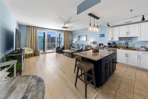A modern living space with a kitchen, dining area, and a balcony with a city view. - Laketown Wharf (Panama City Beach)