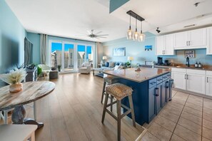 A modern kitchen with a central island, white cabinets, and a view of the city. - Laketown Wharf (Panama City Beach)