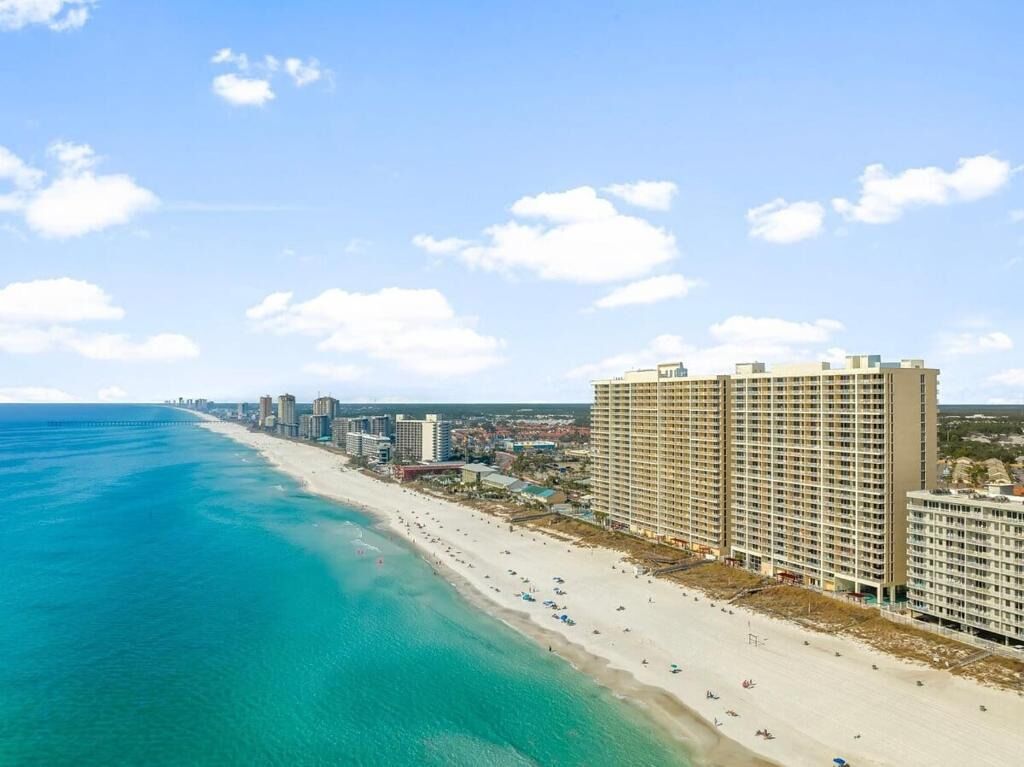 A coastal hotel with a beachfront view, multiple floors, and a sandy beach.