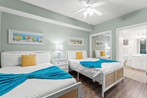 A bedroom with two beds, a ceiling fan, and artwork on the walls. - Majestic (Panama City Beach)