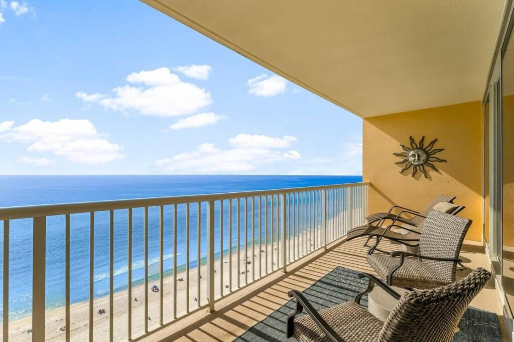 A balcony with a view of the ocean, a sun decoration, and wicker furniture.