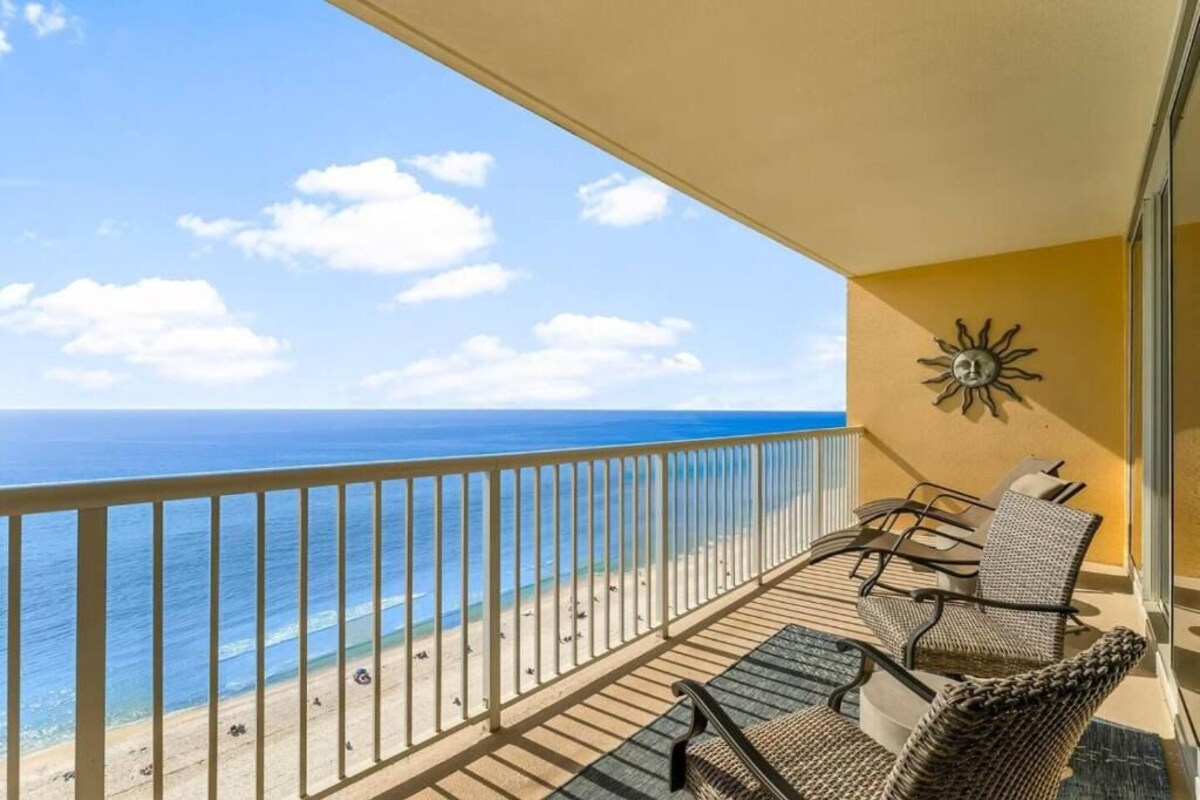 A balcony with a view of the ocean, a sun decoration, and wicker furniture.