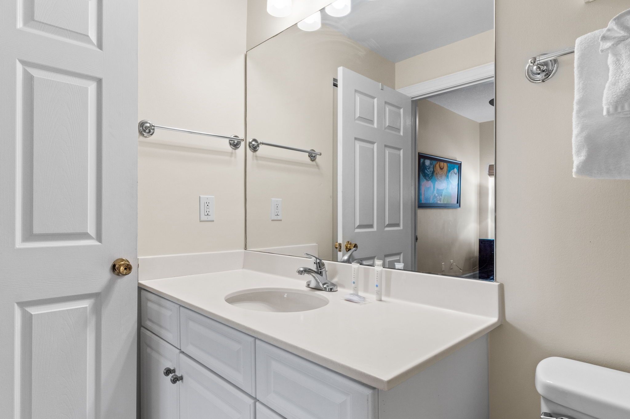 A bathroom with a white sink, a mirror, and a towel rack.