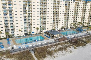 A high-rise hotel with multiple balconies, a pool area with lounge chairs, and a beachside location. - Regency Towers (Panama City Beach)