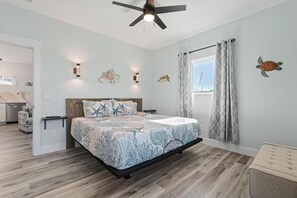 Ein Schlafzimmer mit einem Bett, einem Deckenventilator, einem Fenster mit Vorhängen und einer Wand mit einer Schildkrötenverzierung.