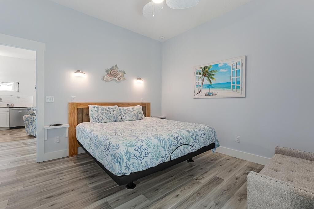 A bedroom with a bed, a painting of a beach scene, and a wooden headboard.