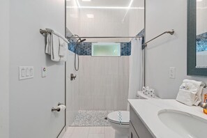 Ein modernes Badezimmer mit einer in Glas abgeschirmten Dusche, einer Toilette mit Bidetfunktion und einem Waschbecken mit Spiegel darüber.