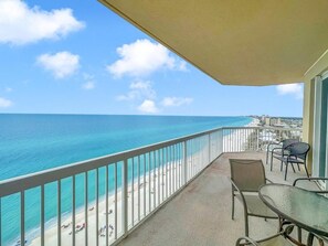 Ein Balkon mit Blick auf Strand und Meer, inklusive Tisch und Stühlen.