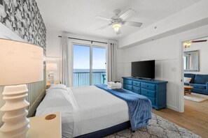 Ein Hotelzimmer mit Bett, Fernseher, Kommode und Balkon mit Aussicht.