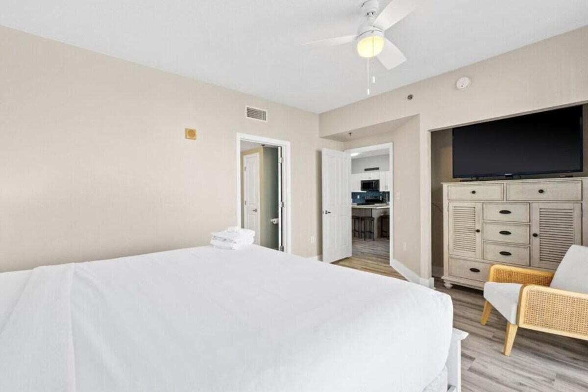 A hotel room with a bed, a television, a dresser, and a chair.