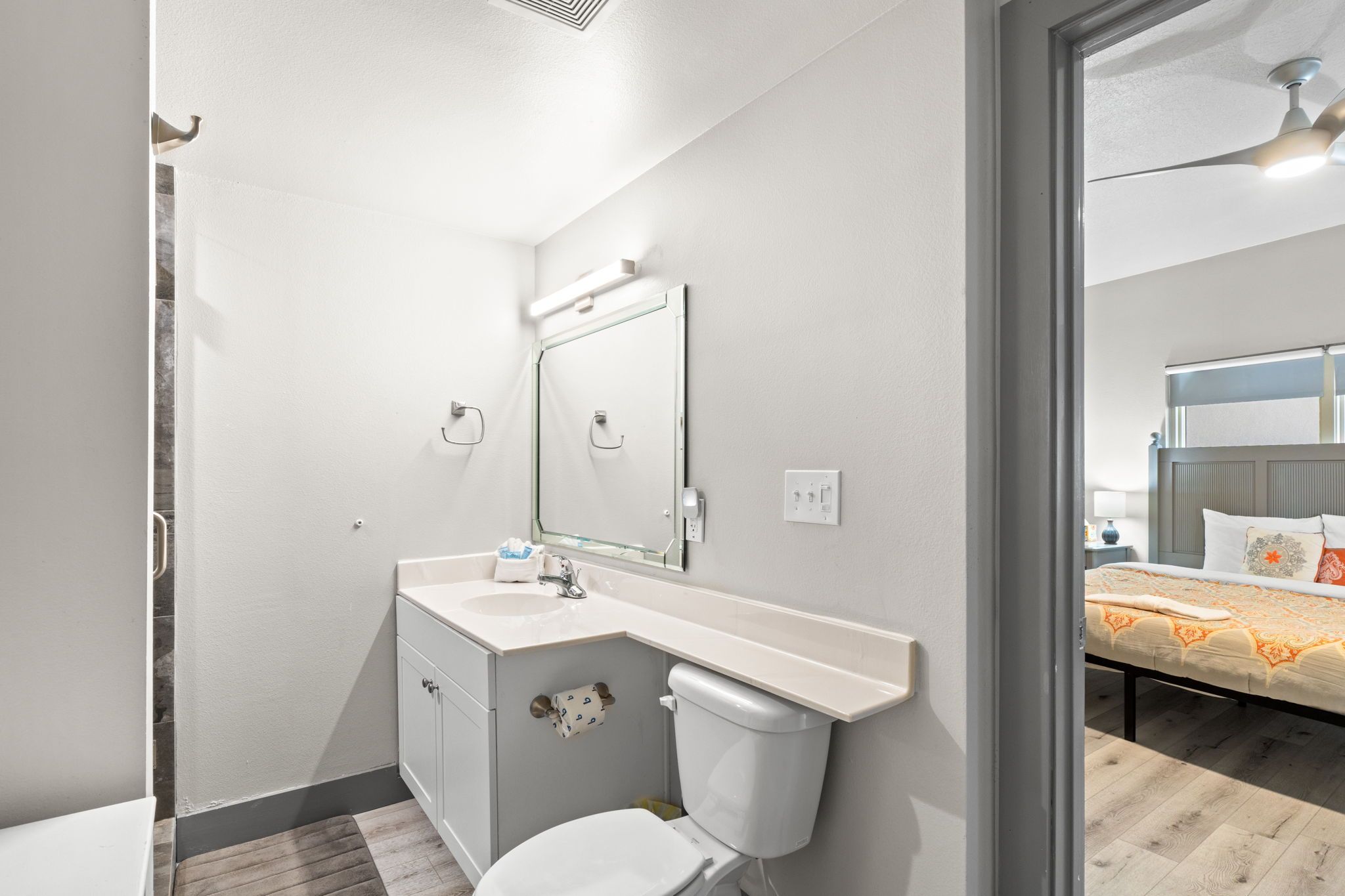 A bathroom with a toilet, sink, and mirror.