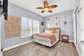 A bedroom with a bed, a ceiling fan, a window with blinds, and a wall-mounted shelf. - Shores Of Panama (Panama City Beach)