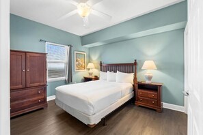 A bedroom with a bed, nightstands, a ceiling fan, a wardrobe, and a window with blinds. - Sunrise Beach (Panama City Beach)