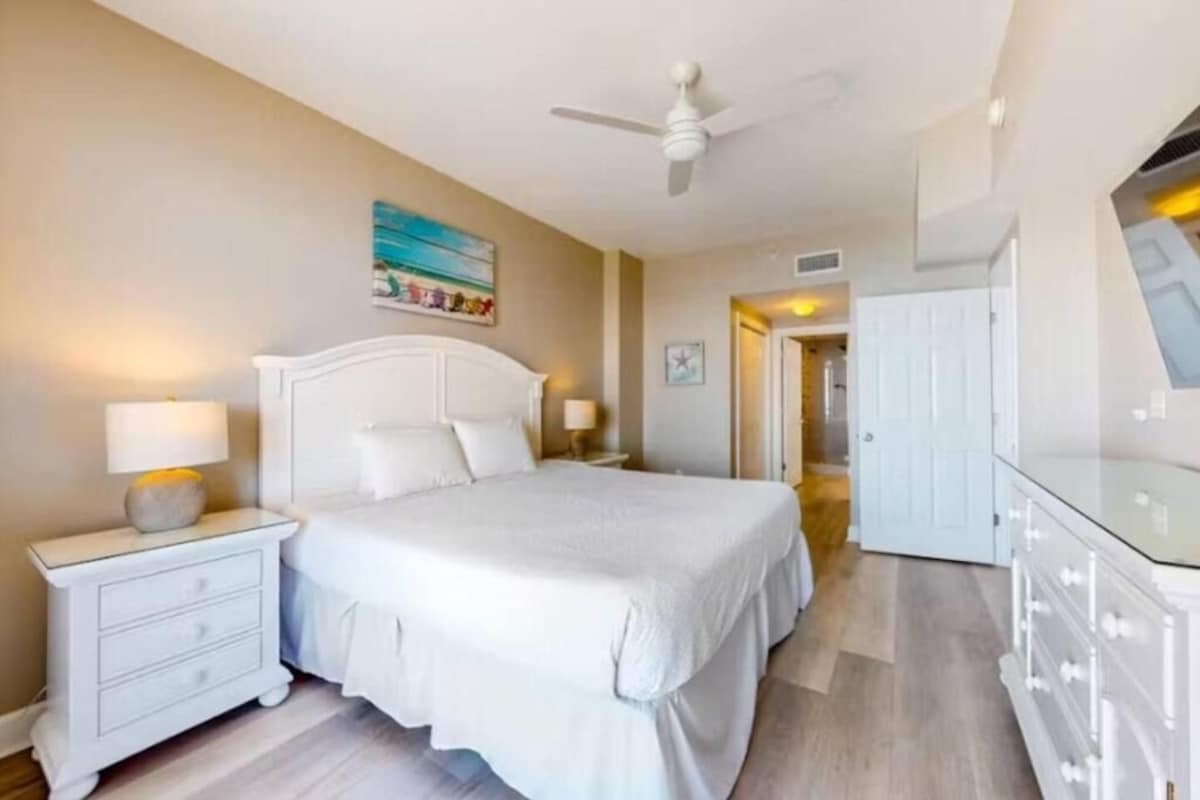 A bedroom with a bed, nightstands, a dresser, and a ceiling fan.
