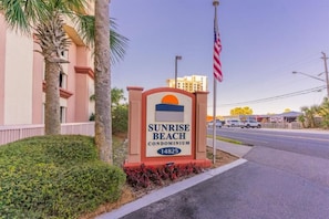 A condominium sign with the name 'Sunrise Beach' and the number '14825' on a sunny day. - Sunrise Beach (Panama City Beach)
