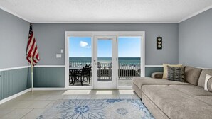 Ein Zimmer mit Blick auf den Strand, eine Couch, ein gemustertes Teppich und eine amerikanische Flagge.