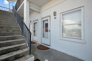 A building with a staircase leading to a landing, a white exterior, and a large window. - Surf Club (Panama City Beach)