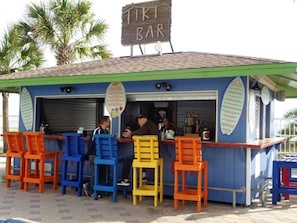 A Tiki Bar with outdoor seating and a closed shutter. - The Summit (Panama City Beach)