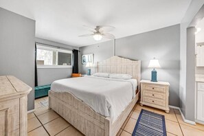 A bedroom with a bed, nightstands, a lamp, a ceiling fan, and a window. - The Summit (Panama City Beach)