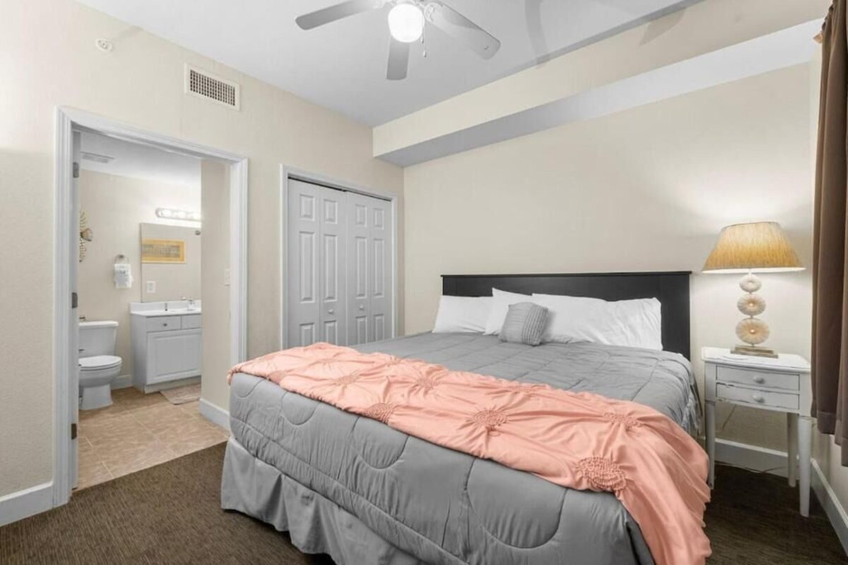 A bedroom with a bed, bedside table, and a ceiling fan.