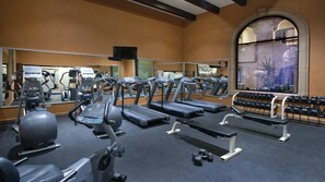 Una palestra con tapis roulant, macchinari ellittici e manubri.