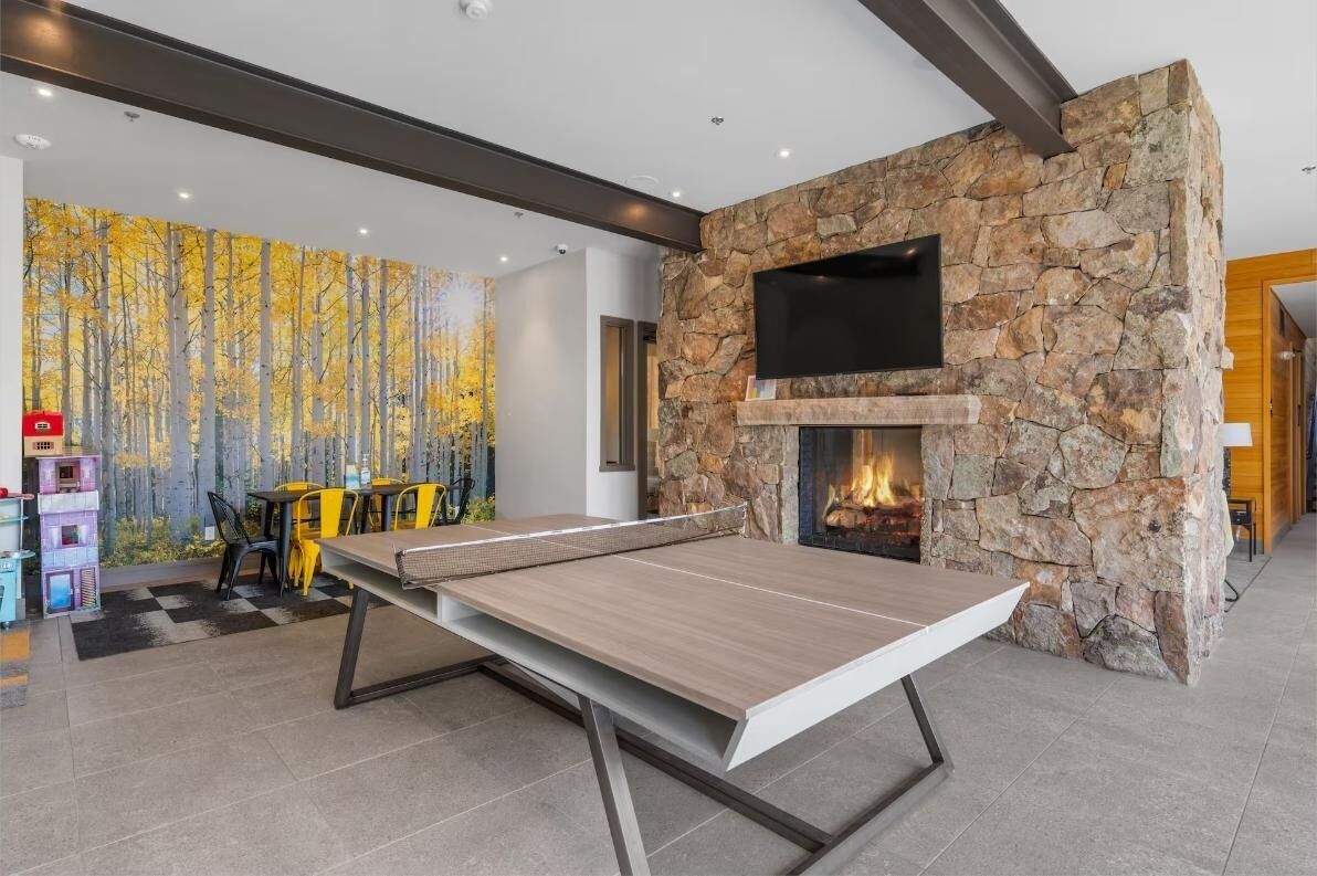 Une table de ping-pong dans une pièce avec un mur en pierre et une cheminée.
