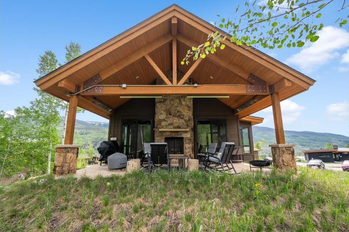 Un chalet moderne doté d’une cheminée en pierre, d’un espace extérieur aménagé et offrant une vue sur les montagnes.