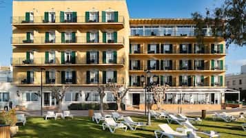 Een hotel met meerdere verdiepingen, balkons, terraszitplaatsen en een verzorgd gazon.