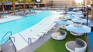 Un espace piscine avec des chaises longues, des parasols et un bâtiment en arrière-plan.