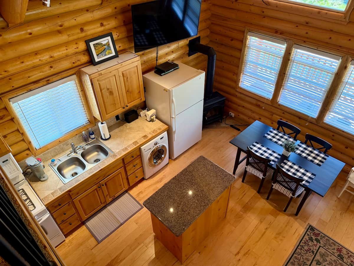 Une cuisine compacte équipée d’un évier, d’une cuisinière et d’un coin repas avec une table et des chaises.