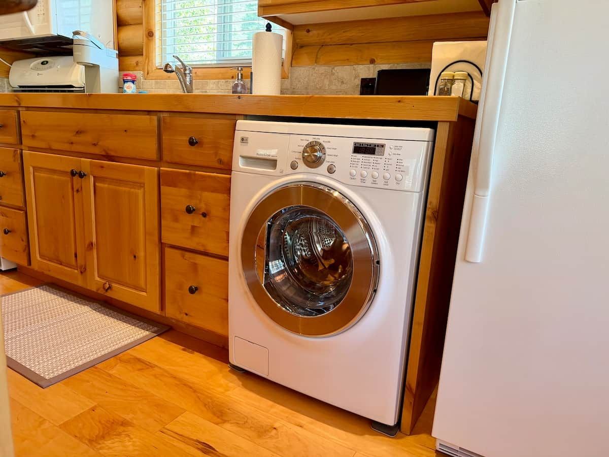 A compact kitchen with wooden cabinets, a built-in washing machine, and a refrigerator.