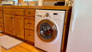 A compact kitchen with wooden cabinets, a built-in washing machine, and a refrigerator.
