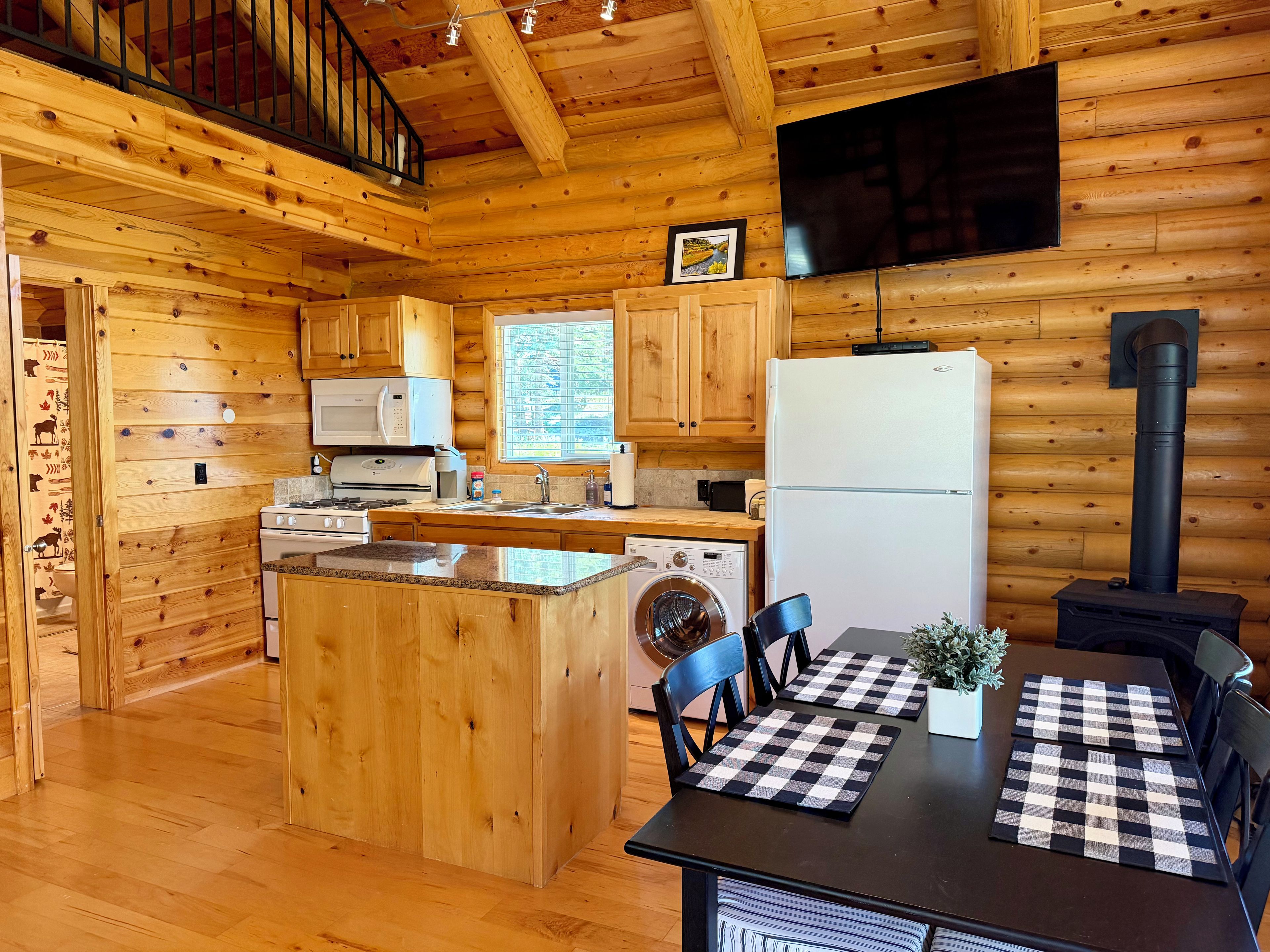 L’intérieur d’une cabane en rondins comprend une cuisine, un coin repas et un escalier.
