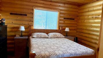 Une chambre à coucher dans une cabane en bois, avec un lit, deux tables de chevet et une fenêtre.