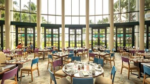 A spacious dining area with large windows, multiple tables, and chairs arranged for dining. - 3BR Presidential Ocean View at Margaritaville Rio Mar on Puerto Rico Coast (Rio Grande)
