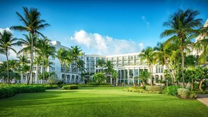 Een hotel met een modern architectonisch ontwerp, met meerdere verdiepingen en een verzorgd gazon met palmbomen.