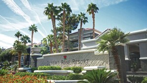 Une enseigne pour le Desert Rose Resort, avec des palmiers et un ciel dégagé.