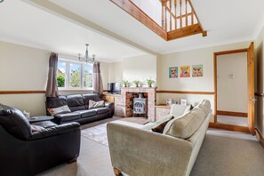 A living room with a fireplace, two sofas, a television, and a wooden staircase.