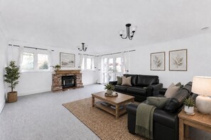 Ein großzügiger Wohnraum mit Kamin, einer schwarzen Ledersofa und einem Couchtisch.