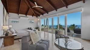 A spacious living area with a large sliding glass door leading to a balcony with a view of the ocean. - Luxury Villa Sol y Mar in Vieques (Vieques Island)
