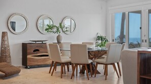 A modern dining area with a round table, six chairs, and three wall-mounted mirrors. - Luxury Villa Sol y Mar in Vieques (Vieques Island)