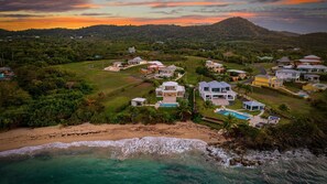 Une zone résidentielle côtière avec des maisons, une plage et une montagne en arrière-plan.