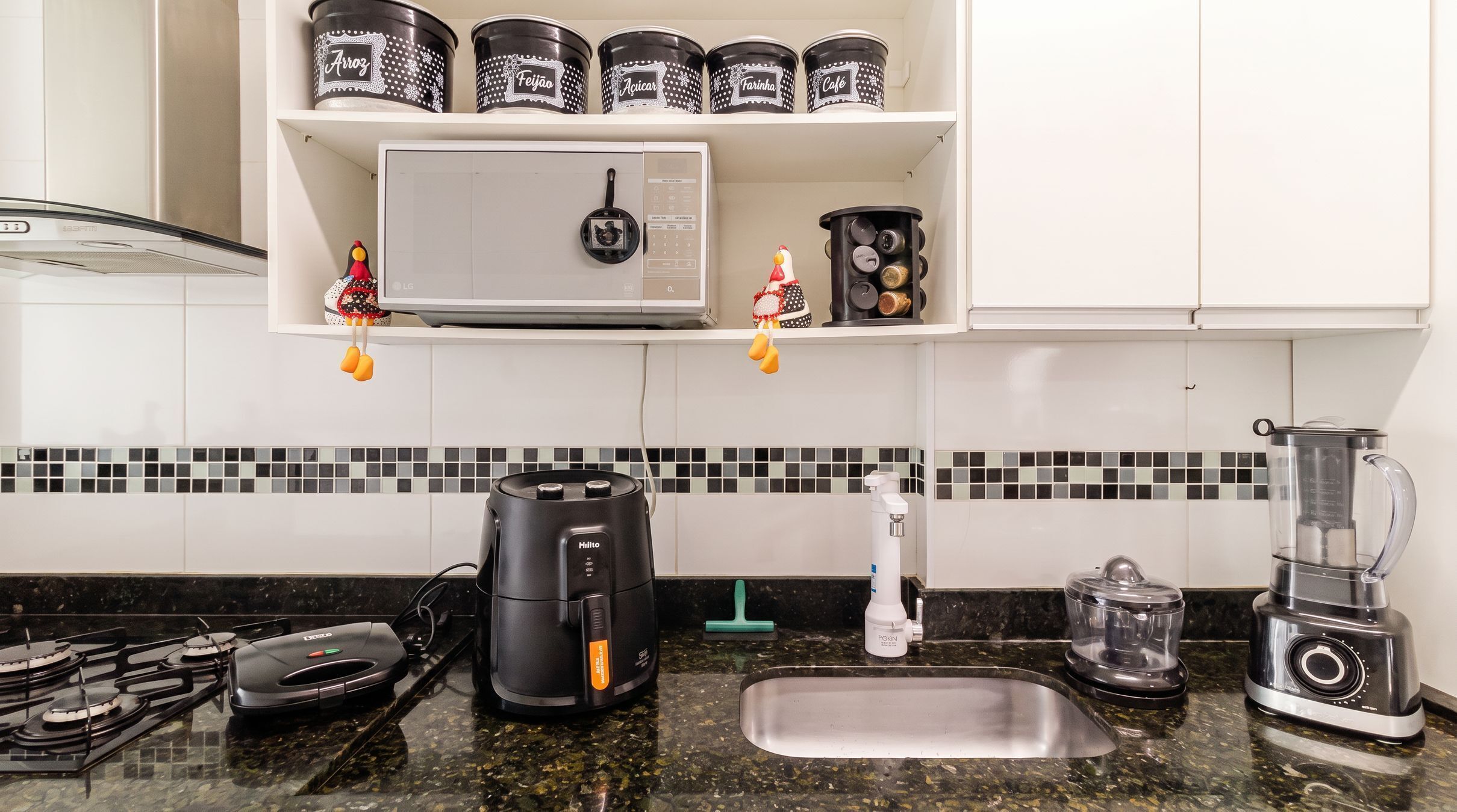 A kitchen with a gas stove, a coffee maker, a blender, and a kettle.