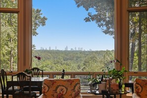 Una habitación con amplias ventanas que ofrecen vistas a un horizonte urbano y una colina boscosa.