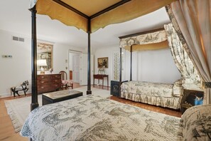 Ein Schlafzimmer mit Himmelbett, einer Couch, einem Schminktisch und einem Sessel.