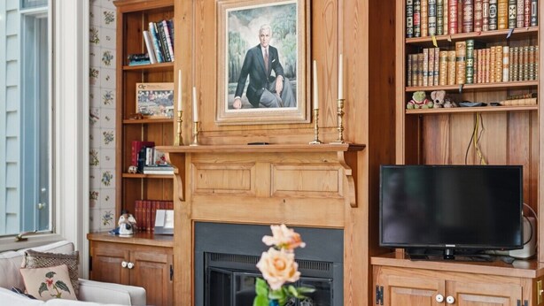 Ein Wohnzimmer mit Kamin, Fernseher und einer Bücherwand voller Bücher.