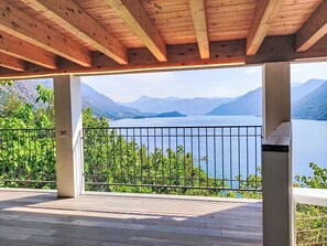 Ein überdachter Außenbereich mit Blick auf einen See und Berge.
