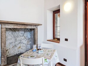 Ein Zimmer mit Kamin, einem Tisch mit Blumenmuster und einem Fenster mit Blick.